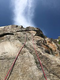 Low angle view of rope on rock formation against sky