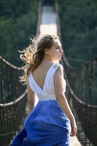 Side view of young woman standing against blurred background