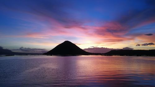 Scenic view of lake and volcano against sky during sunrise
