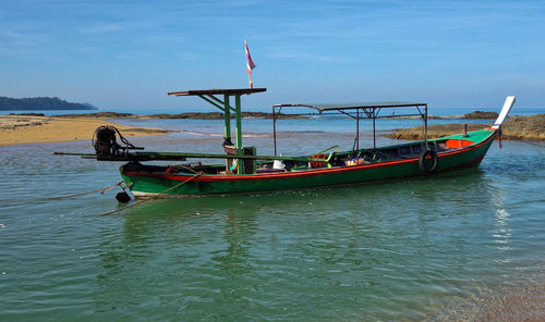People on boat moored in sea against sky