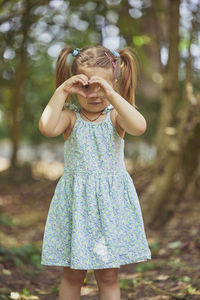 Portrait of young woman standing against trees