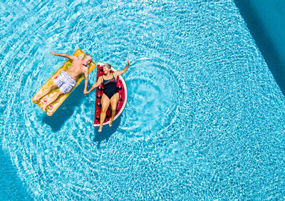 Directly above shot of man and floating on raft inn swimming pool