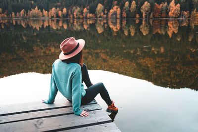 Rear view of woman sitting on pier