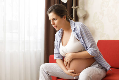 Young woman sitting on sofa at home