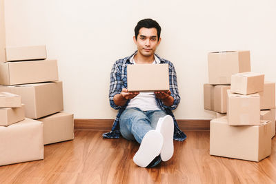 Portrait of young man sitting on hardwood floor