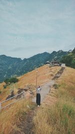 Woman standing on mountain against sky