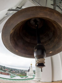 Low angle view of electric lamp hanging by building against sky