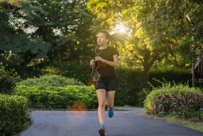 Full length of woman running on footpath in park