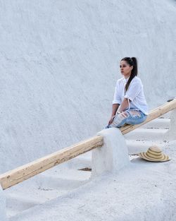 Side view of a young woman leaning against wall