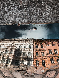 Reflection of building in water puddle on footpath