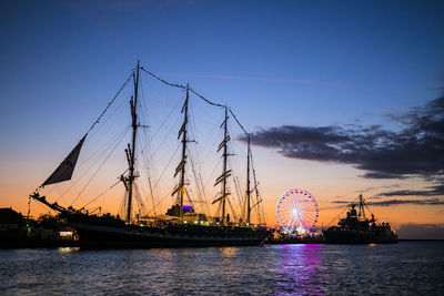 Cranes by sea against sky at night