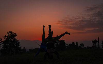 Silhouette people on field against sky during sunset