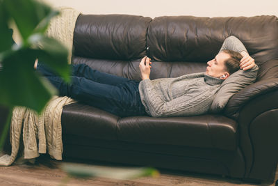 Low section of woman sitting on sofa at home