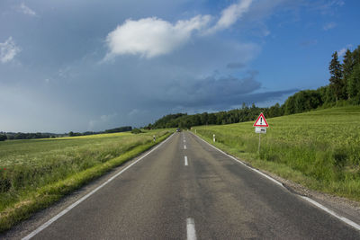 Road amidst field against sky