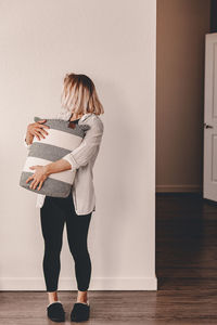 Full length of woman holding container while standing at home