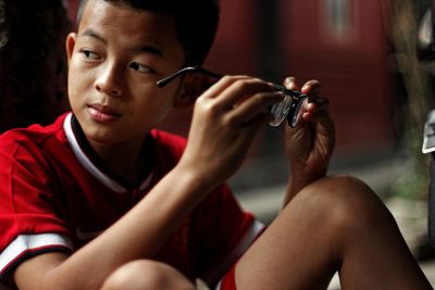 Close-up of boy holding eyeglasses while looking away