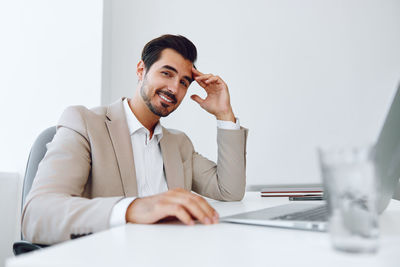 Businesswoman using laptop while sitting on table against white background