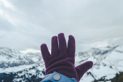 Person hand on snowcapped mountain against sky