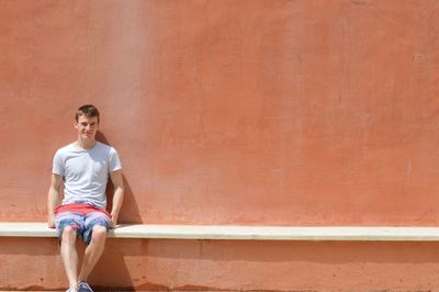 Portrait of smiling young man leaning on wall