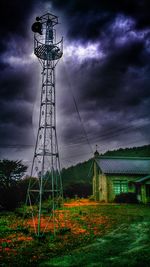 Low angle view of electricity pylon on field against cloudy sky