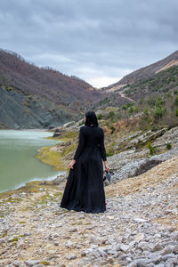 Rear view of woman standing on mountain against sky