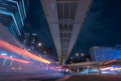 Light trails on road in city against sky at night