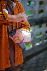 Midsection of woman holding orange while standing outdoors