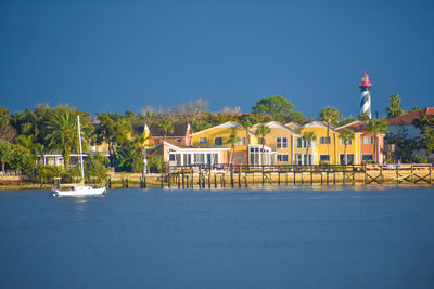 Houses by building against clear blue sky