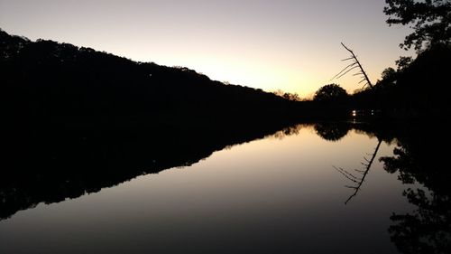 Reflection of silhouette trees on lake against sky during sunset