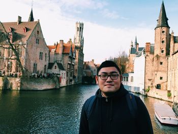 Portrait of young man standing by buildings in city