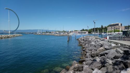 Sailboats on sea by city against sky