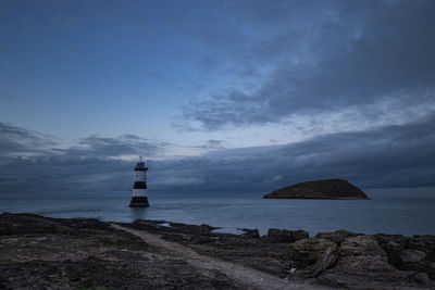 Lighthouse by sea against sky