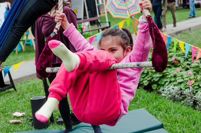 Close-up of girl sitting on swing at park 