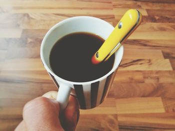 Cropped image of hand holding black coffee in cup