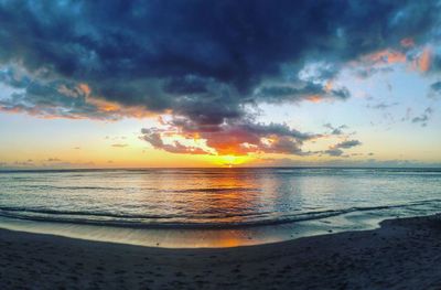 Scenic view of sea against dramatic sky during sunset