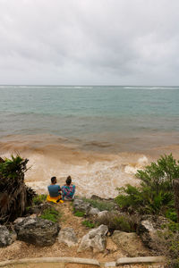 Rear view of men at beach against sky