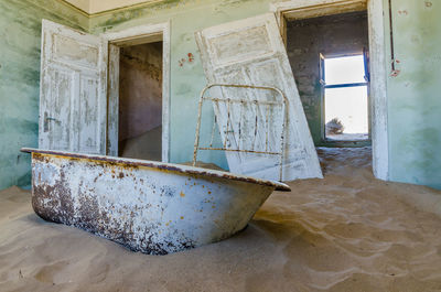 Abandoned house filled with sand and old bathtub at former german mining town kolmanskop near luderitz, namibia