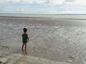 Full length rear view of boy walking on beach