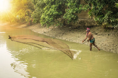Man throwing fishing net in river