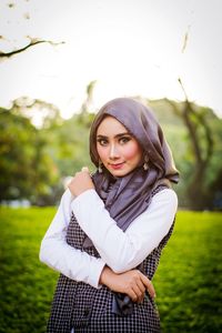 Portrait of woman in hijab standing at park during sunset