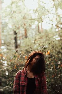 Young woman standing against plants