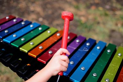 Cropped hand of child playing xylophone outdoors
