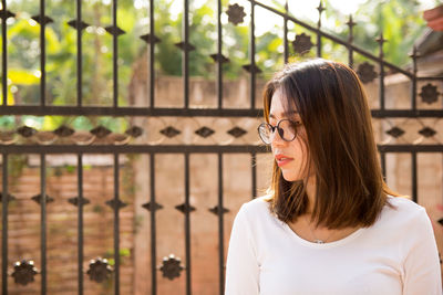 Woman looking down against gate