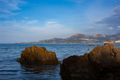 Rocks on sea shore against sky