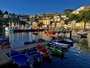 Sailboats moored at harbor against buildings in city