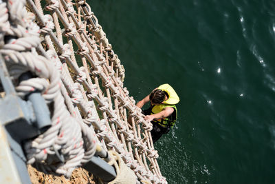 High angle view of man climbing ropes over lake