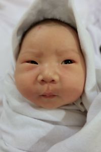 Portrait of cute baby girl lying on bed