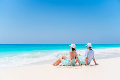 People on beach against clear blue sky