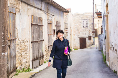 Portrait of smiling woman standing against building