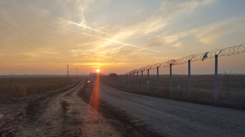 Empty country road against orange sky
